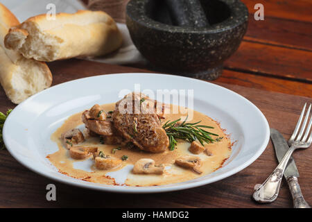 Concept: restaurant menus, healthy eating, homemade, gourmands, gluttony. White plate of pork medallions with mushroom sauce on weathered wooden table Stock Photo