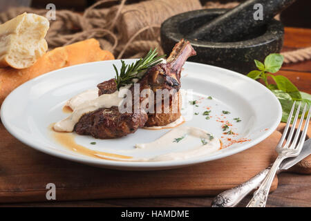 Concept: restaurant menus, healthy eating, homemade, gourmands, gluttony. White plate of lamb rack on wooden table and ingredients on background. Stock Photo