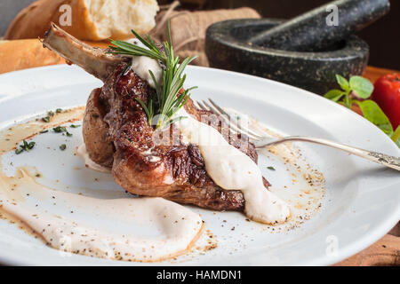 Concept: restaurant menus, healthy eating, homemade, gourmands, gluttony. White plate of lamb rack on wooden table and ingredients on background. Stock Photo