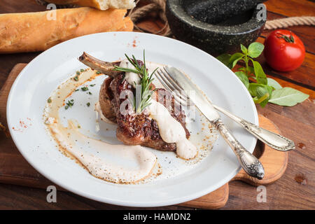 Concept: restaurant menus, healthy eating, homemade, gourmands, gluttony. White plate of lamb rack on wooden table and ingredients on background. Stock Photo