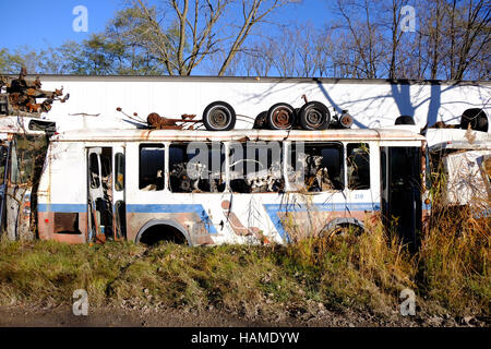 An old city bus sits abandoned in a junkyard with engines stored inside of it in Frankfort, Indiana. Stock Photo