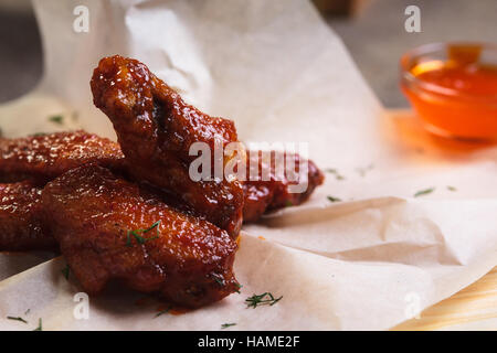 Concept: restaurant menus, healthy eating, homemade, gourmands, gluttony. Chicken wings in spicy sour sauce served on paper with ingredients and vinta Stock Photo