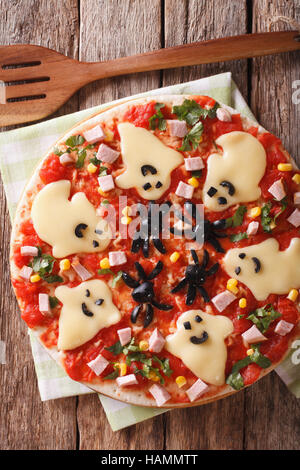 Pizza Halloween with ghosts cheese and olives spiders close-up on the table. Vertical view from above Stock Photo