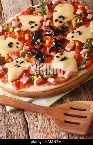 Halloween Food: Pizza with ghosts and spiders close-up on the table. vertical Stock Photo