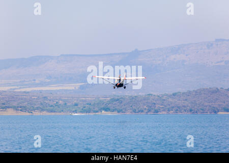 Plane Microlight pilot low flying aircraft photo over lake waters ...