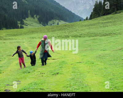 A Kyrgyz family plays and laughs running through a valley in the mountains of Karakol Stock Photo