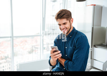 Picture of young man using a smartphone and smiling. Looking at smartphone. Stock Photo