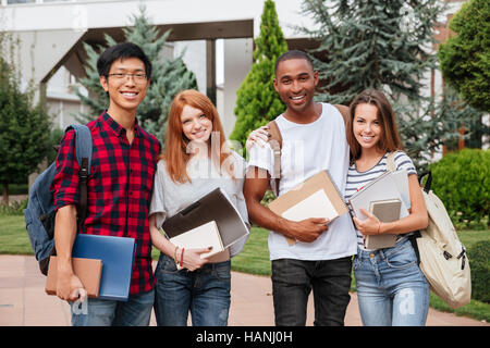 Multiethnic group of cheerful young students standing together outdoors Stock Photo