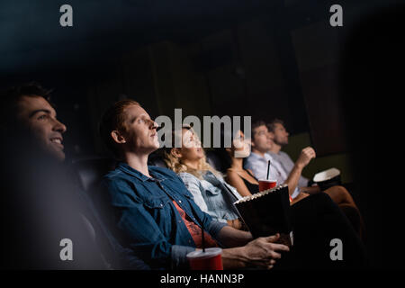 Young man with friends in cinema hall watching movie. Group of people watching movie in theater. Stock Photo