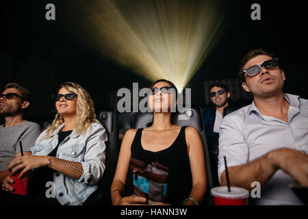 Group of young people watching 3d movie in theater. Young men and women wearing 3d glasses in cinema hall. Stock Photo