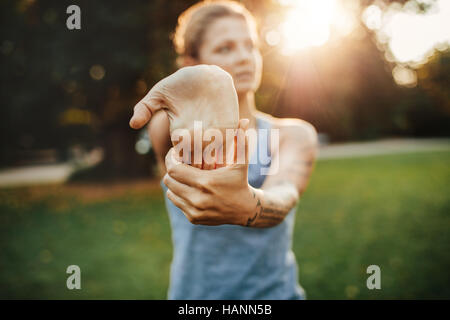 Young woman stretching hand muscles before workout. fitness female stretching at the park. Stock Photo
