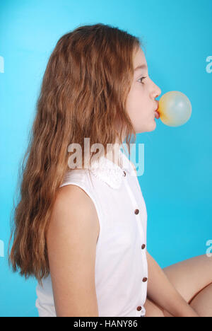 Young girl doing bubble with chewing gum blue background Stock Photo