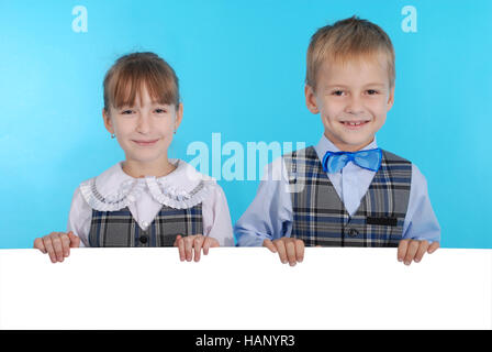 Boy and girl smiling and holding a white banner isolated on blue background Stock Photo