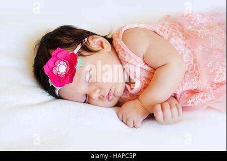 Close-up beautiful sleeping baby girl. Newborn  , asleep on a blanket.  portrait of  , age 2 months.    wearing  large, fabric rose headband. Closeup photo Stock Photo