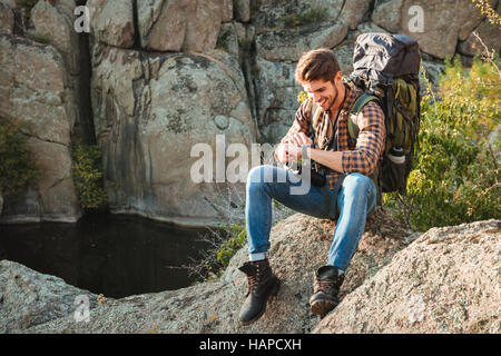 Tourist man sitting on rock looking at wristwatch. near the canyon Stock Photo