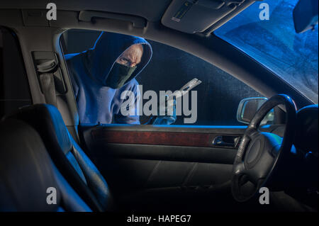 Car thief looking to break into a locked vehicle at night Stock Photo