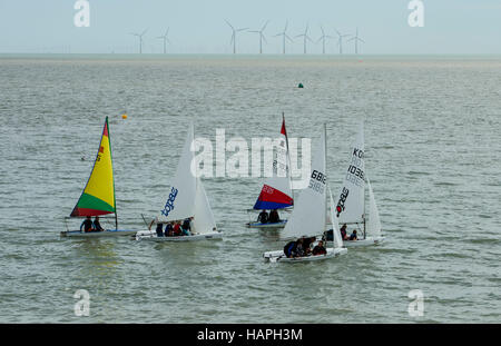 A group of small sailing dinghies containing young people on the sea in a race. Stock Photo