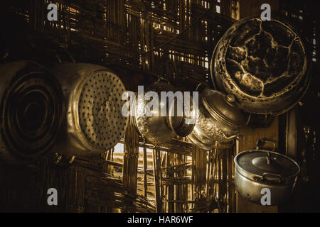 battered old pots and pans hanging on a bamboo wall Stock Photo