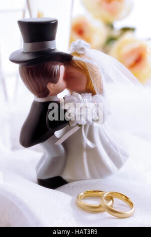 Bride and groom wedding figurines behind wedding rings Stock Photo