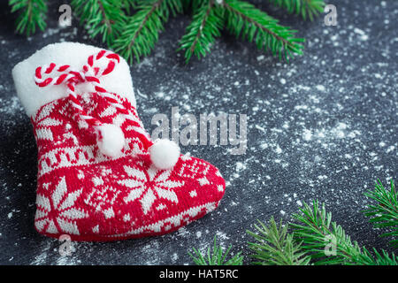Christmas and New Year winter holiday snowbound composition of red stocking on black space background with green fir tree branches Stock Photo