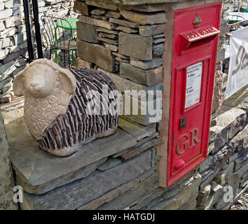 Red post box in slate dry stone wall with Lakeland sheep sculpture, Elterwater, English Lake District, Cumbria, UK. Stock Photo