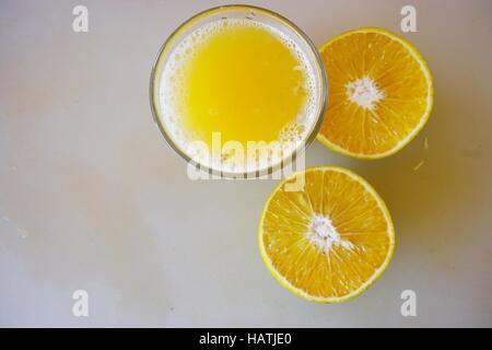 A glass of freshly squeezed tangerine juice with tangerines cut in half Stock Photo