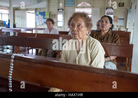 Catholics attend evening prayers at St Peter's Chapel, a small wooden building in Dalat, Mukah Division, Sarawak, Malaysia. Stock Photo