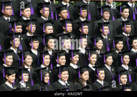 Crowd of student graduate class in caps and gowns standing in commencement event at university. Stock Photo