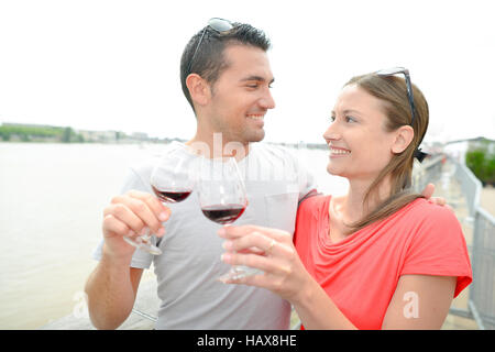 Couple stood next to river, holding glass wine Stock Photo