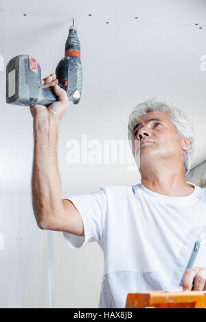 Mason drilling a hole in the ceiling Stock Photo
