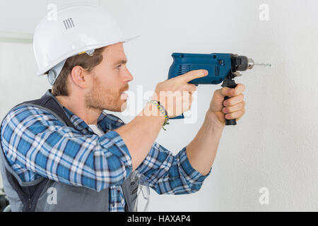 young handsome handyman using a drill at work Stock Photo