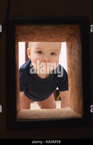 Little child looks to hole in the wall Stock Photo