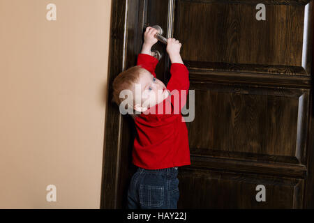 little boy tries to open door Stock Photo