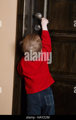 little boy tries to open door Stock Photo