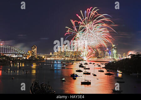 Multi colour light balls during new year fireworks in Sydney city CBD elevated view over blurred harbour waters towards Harbour bridge and Sydney Land Stock Photo