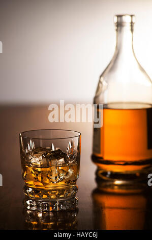 Whiskey with ice in glass and bottle on wooden background Stock Photo