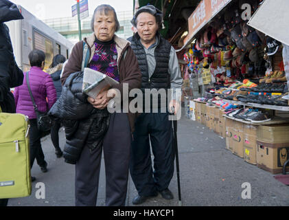 An elderly Asian couple waking together in Chinatown, downtown Flushing, Queens, New York City. Stock Photo