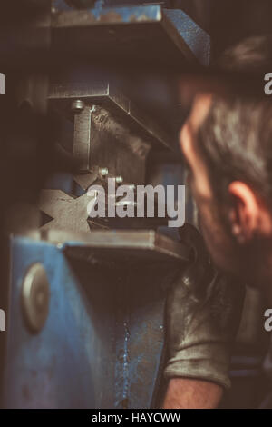 Worker at factory with industrial machine for bending of metal pipes ...