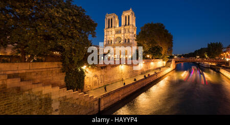 Notre Dame de Paris cathedral illuminated at twilight with the Seine River and the Pont au Double. Ile de La Cite, Paris, France
