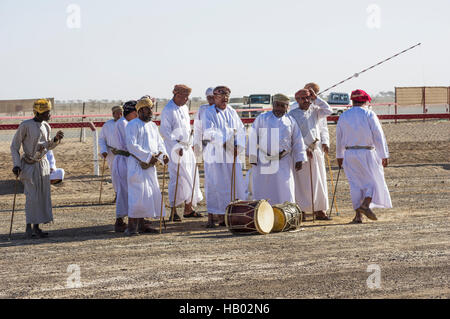 Musicians playing and singing traditional Omani music with instruments at a camel race in the desert in Oman Stock Photo