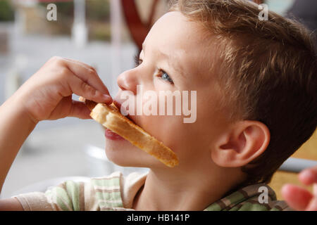 little boy eating piece of white toast and butter Stock Photo