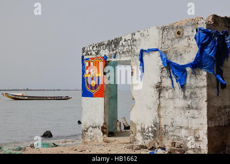Diogue island, Senegal-April 15, 2014: The ruins of a deserted shop on the shore facing the mouth of the Casamance river still show traces of decorati Stock Photo