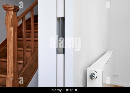 White radiator on wall with sliding door in an appartment with wooden floor Stock Photo