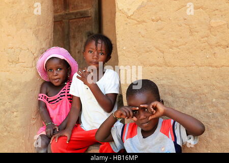 Mlomp-Oussouye, Senegal-April 16, 2014: Kids of Diola people wait to go to morning school while chatting with tourists visiting their village Stock Photo