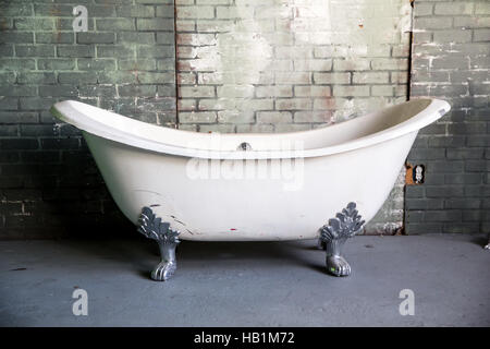 A clawfoot tub sits next to a brick wall Stock Photo