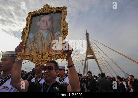 Bangkok, Thailand. 5th Dec, 2016. A man holds a portrait of the late King Bhumibol Adulyadej during a merit-making ceremony on the Bhumibol Bridge in Bangkok, Thailand, Dec. 5, 2016. Over 20,000 people gathered at Bangkok's Bhumibol Bridge to attend a merit-making ceremony marking the 89th birthday anniversary of Thailand's late King Bhumibol Adulyadej on Monday morning. Credit:  Rachen Sageamsak/Xinhua/Alamy Live News Stock Photo