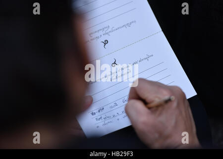 Bangkok, Thailand. 5th Dec, 2016. A well-wisher writes down her wishes on a card while attending a merit-making ceremony for the late King Bhumibol Adulyadej on the Bhumibol Bridge in Bangkok, Thailand, Dec. 5, 2016. Over 20,000 people gathered at Bangkok's Bhumibol Bridge to attend a merit-making ceremony marking the 89th birthday anniversary of Thailand's late King Bhumibol Adulyadej on Monday morning. Credit:  Li Mangmang/Xinhua/Alamy Live News Stock Photo