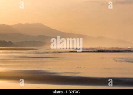 Silhouettes of two people walking on the beach Stock Photo