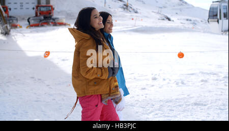 Two young women walking through snow at a resort Stock Photo