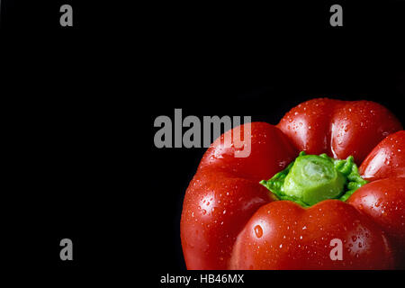 Closeup view of red pepper with water drops. Pepper is on a black background. Free place for your text is in the lefs side of the photo. Stock Photo
